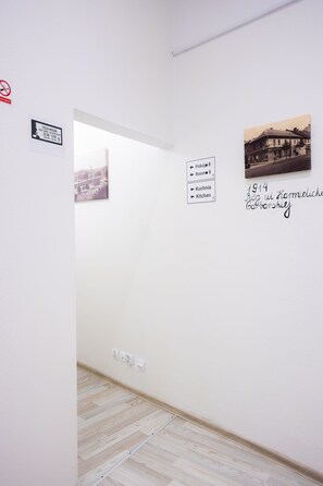 A hallway with a white wall, a framed photograph, and directional signs. - FiveHostel (Kraków)