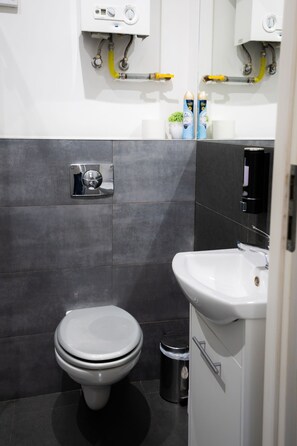 Ein modernes Badezimmer mit Toilette, Waschbecken und Mülleimer.