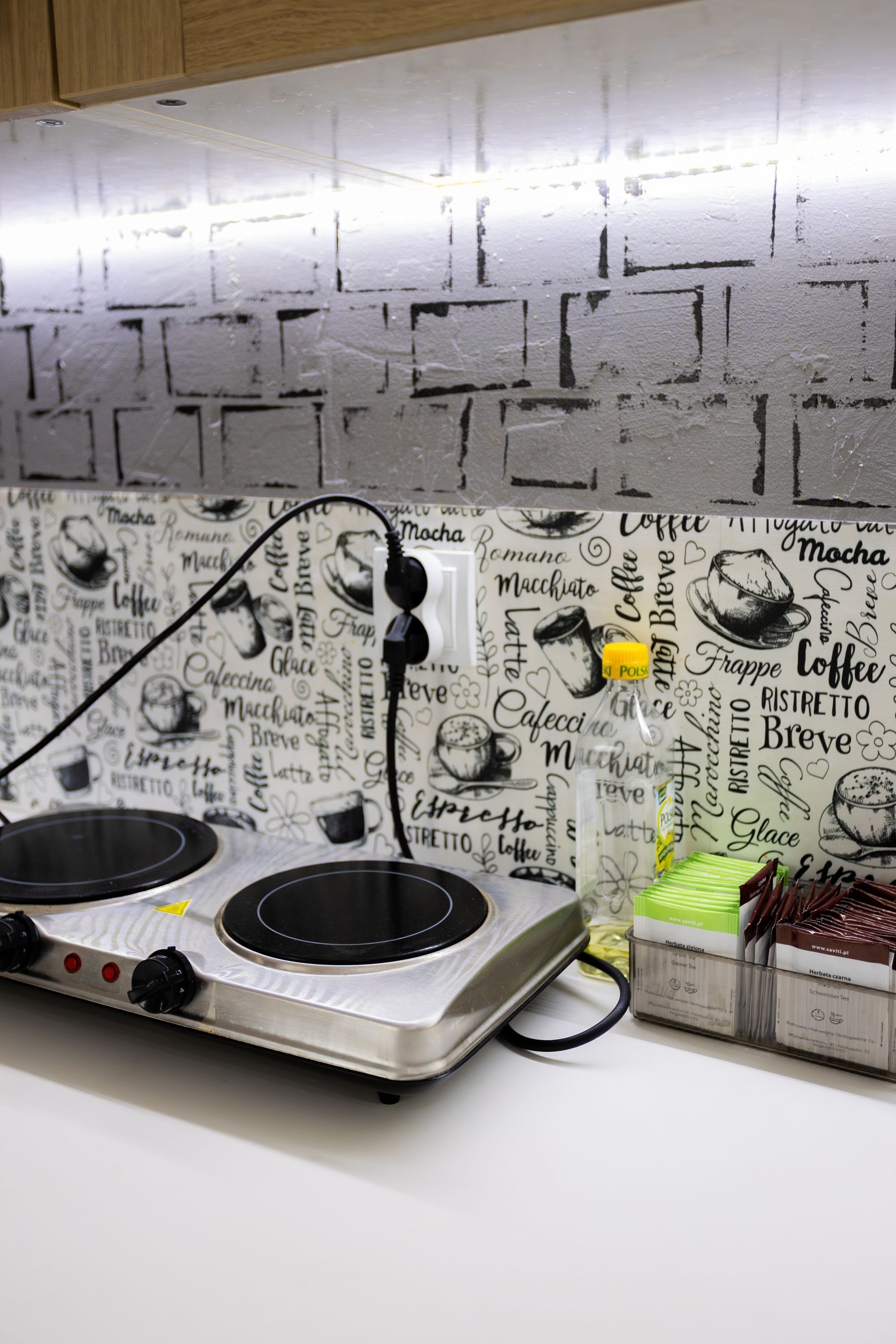 Una cocina con una moderna placa de inducción y un salpicadero decorado con motivos de café.