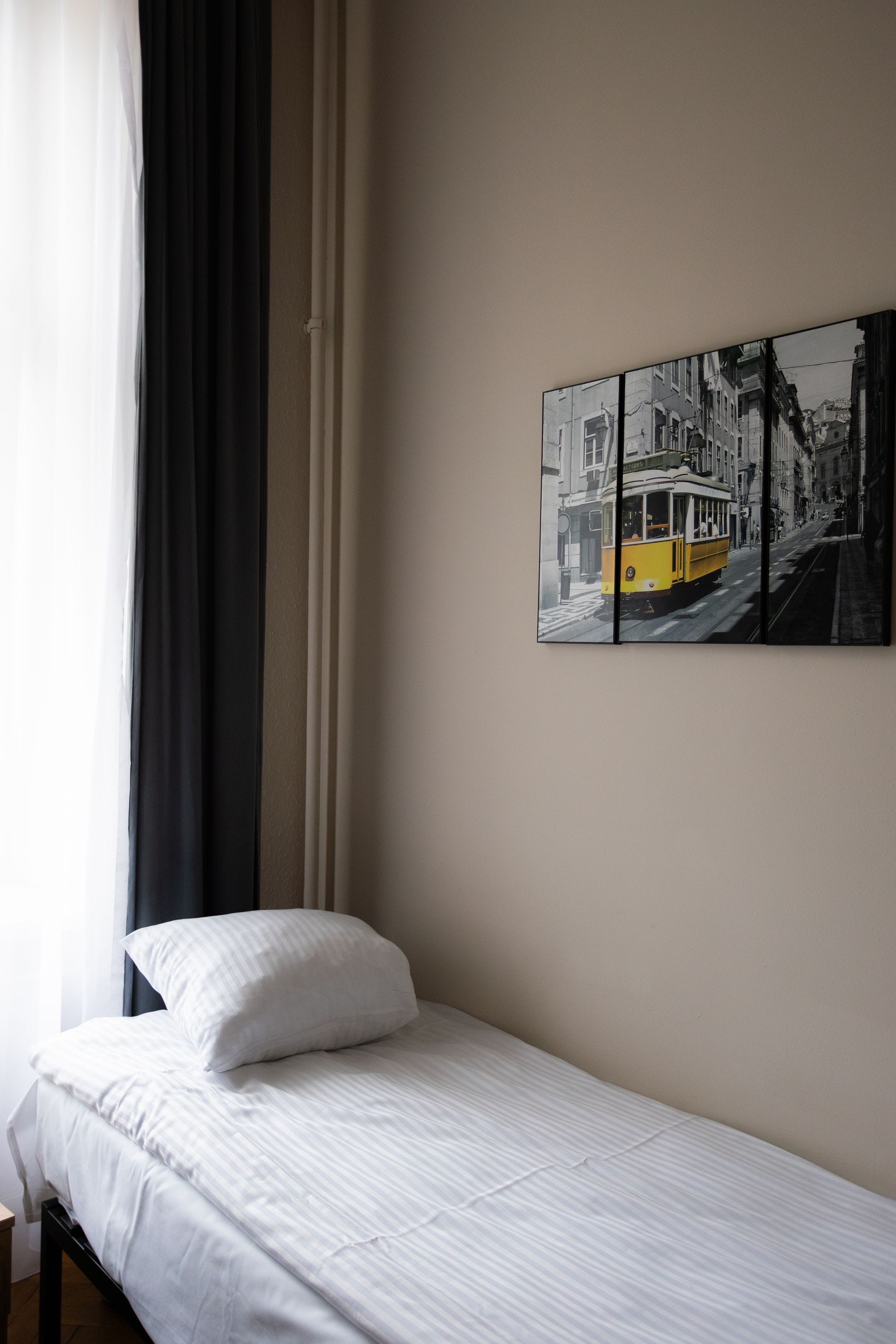 Ein Einzelbett mit weißer Bettwäsche in einem Zimmer mit schlichter Wand.
