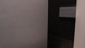 Un baño moderno con inodoro, una pequeña planta en maceta y un dispensador de toallas.