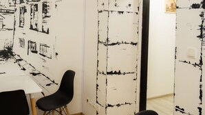 A room with a whiteboard featuring black sketches of buildings, a white table, two black chairs, and a wooden floor. - FiveHostel (Kraków)