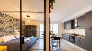A modern apartment with a bed, a dining area, and a kitchen. - Urban Chic Luxury Suite Apartments (Roma)