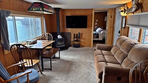 Una sala de estar acogedora con detalles de madera, una chimenea, un televisor montado en la pared y un sofá.