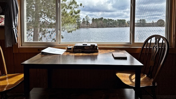 Una mesa de madera con vistas a un lago y árboles a través de una ventana.