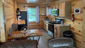 A compact kitchen with wooden walls, a dining area with a table and chairs, and a small kitchenette. - Shady Rest Cabin #1, Sunset Views, Beach, Pets Welcome, Swimming, Firepit (Rhinelander)