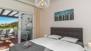 Een slaapkamer met een groot bed, uitzicht op de omgeving, een schilderij aan de muur en een kroonluchter.