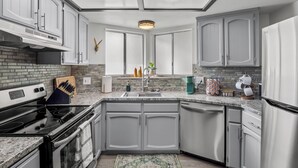 A modern kitchen with white cabinets, a black stove, and a skylight.