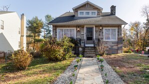 A two-story house with a stone facade, a front porch, and a stone pathway leading to the entrance. - Spacious 5-bedroom Pineapple House in wonderful Pikesville/10PPL/Pets/ WiFi (Pikesville)