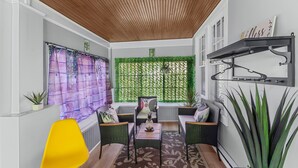 A cozy room with a wooden ceiling, a green plant wall, a yellow chair, and a small table with a vase. - Spacious 5-bedroom Pineapple House in wonderful Pikesville/10PPL/Pets/ WiFi (Pikesville)