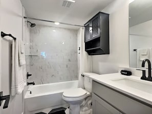 A modern bathroom with a bathtub, toilet, and sink. - Upscale suite w/ pool & extra large balcony (Birmingham)