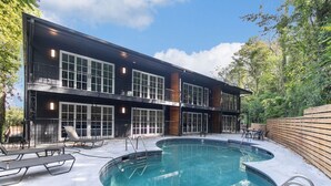 A two-story building with a pool, outdoor seating, and a wooden fence. - Upscale suite w/ pool & extra large balcony (Birmingham)