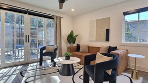 A modern living room with a sofa, two armchairs, a coffee table, and a ceiling fan. - Upscale suite w/ pool & extra large balcony (Birmingham)
