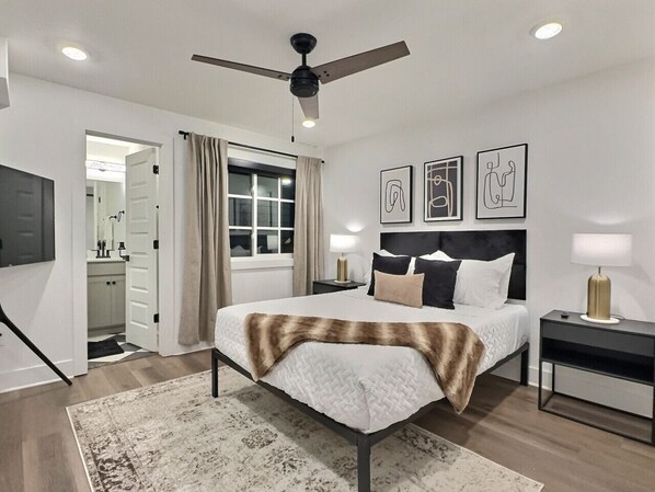 A modern bedroom with a bed, bedside tables, a ceiling fan, and artwork on the wall. - Upscale suite w/ pool & extra large balcony (Birmingham)