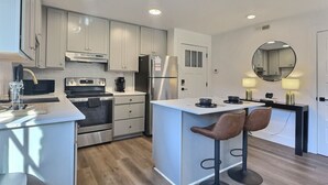 A modern kitchen with a central island, bar stools, and built-in appliances. - Upscale suite w/ pool & extra large balcony (Birmingham)