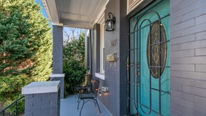 A covered porch with a teal door, a mailbox, and a small seating area. - 3 DC Homes | Sleeps 30 | Group Getaway (Washington)