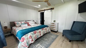 Un dormitorio con cama, cómoda, silla y ventilador de techo.