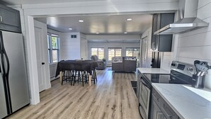 Una cocina moderna con comedor, piso de madera y un amplio ventanal.