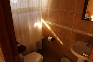 Un baño con inodoro, lavamanos y un perchero para toallas.