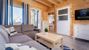 A cozy log cabin interior with a sofa, a small table, and a TV mounted on the wall. - Stunning home in Sarbinowo with WiFi (Sarbinowo)