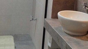 Een badkamer met een douche, een wastafel en een spiegel.