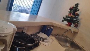Een kleine keuken met een Proctor-Sinclair koffiezetapparaat, een koekenpan en een spoelbak.