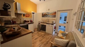 Eine kleine Küche mit Herd, Spüle und einem Essbereich mit Sofa und Tisch.
