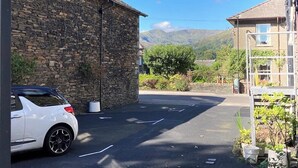 Ein Parkplatz mit einem Steinhaus und einem weißen Auto.