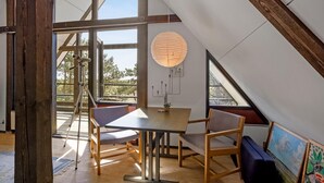 Une pièce spacieuse avec une grande table, deux chaises, une lampe suspendue et un tableau au mur.