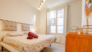 A bedroom with a bed, a wooden dresser, and a window with curtains. - L'Idylle - SAINTE SAVINE (SAINTE SAVINE)