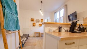 A compact kitchen with a wooden countertop, a kettle, a coffee maker, and a TV mounted above the counter. - L'Idylle - SAINTE SAVINE (SAINTE SAVINE)