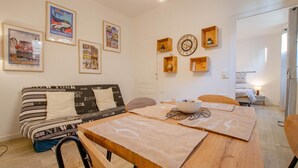 A cozy living area with a sofa, a dining table, and a kitchen in the background. - L'Idylle - SAINTE SAVINE (SAINTE SAVINE)