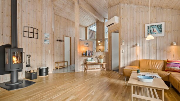 A cozy wooden interior with a central fireplace, a sofa, and a dining table.