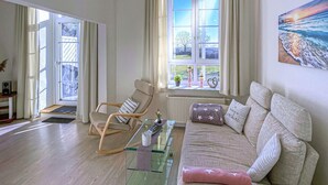 A living room with a sofa, a rocking chair, a glass coffee table, and a view of the outdoors through large windows. - Pet friendly apartment in Hohen Wieschendorf (Hohen Wieschendorf)