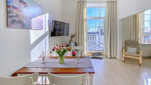 A dining area with a wooden table, white chairs, a vase with flowers, and a TV on the wall. - Pet friendly apartment in Hohen Wieschendorf (Hohen Wieschendorf)