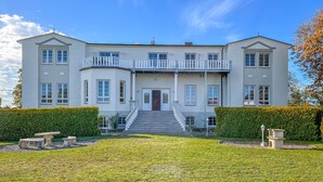A large, two-story building with a symmetrical facade, a central entrance with a staircase, and a balcony on the upper floor. - Pet friendly apartment in Hohen Wieschendorf (Hohen Wieschendorf)