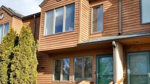 Un edificio in legno su due piani, con ampie finestre e una porta verde.