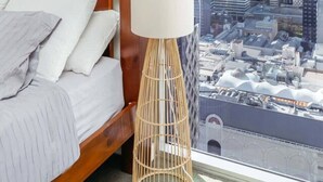 A bedroom with a bed, a bedside lamp, a framed picture, and a large window with a city view. - Great Value CBD 2 Beds Apt Free Carpark/ Pool /Gym (Brisbane City)