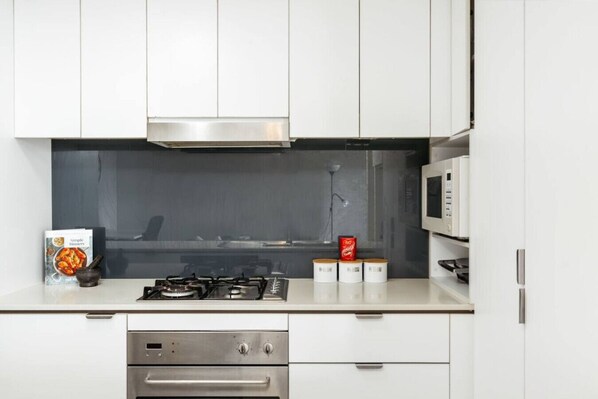 A modern kitchen with white cabinets, a stainless steel range, a microwave, and a gas stove.