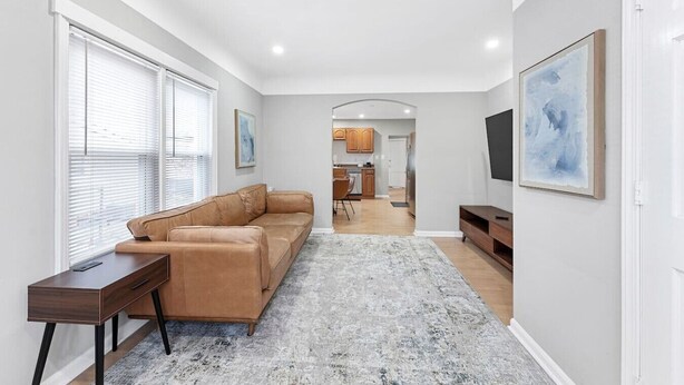A modern living room with a leather sofa, a coffee table, and a TV on a stand. - Spacious Mid Century Modern 1 Bed 1 Bath 65" TV (Wyandotte)