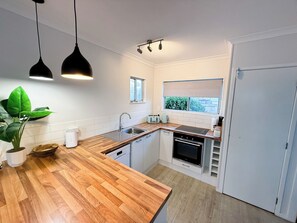 Una cucina compatta con piano di lavoro in legno, un lavello, un tostapane e una finestra con vista su piante.