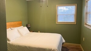 A bedroom with a bed, a ceiling fan, and a window with blinds.
