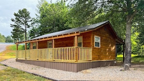 A wooden cabin with a covered porch and a gravel driveway.