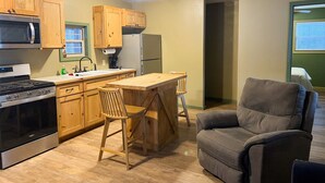 A compact kitchen with wooden cabinets, a built-in microwave, a stove, and a dining area with a table and chairs.