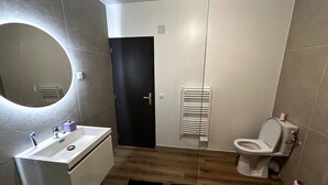 A modern bathroom with a white sink, a toilet, and a towel rack.