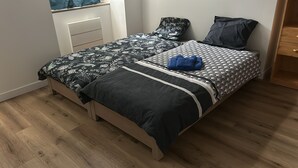 A bedroom with a bed, two pillows, a bedside table, and a wooden wardrobe.