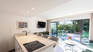 A modern kitchen with a central island, a dining area with a table and chairs, and a large sliding glass door leading to an outdoor patio.