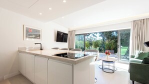 A modern kitchen with a central island, a dining area with green chairs, and a large sliding glass door leading to an outdoor space.