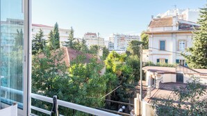 A balcony with a view of a cityscape, including buildings and trees.