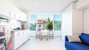 A modern apartment with a kitchen, dining area, and a living room with a large window offering a city view.